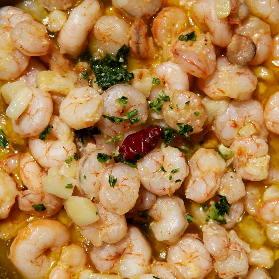 Close-up of Walton's Fresh Fish Seafood garlic shrimp with parsley and a red chili.